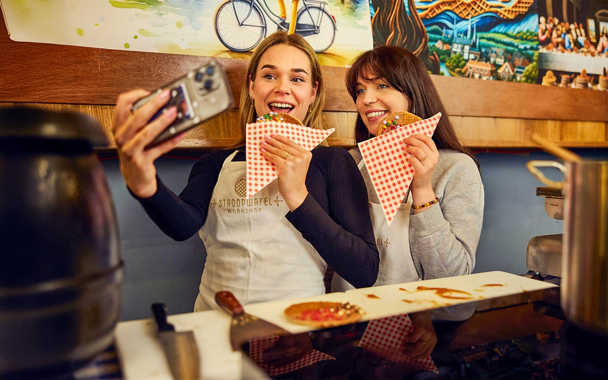 Guests taking a selfie while holding stroopwafels at a Dutch syrup waffle workshop.