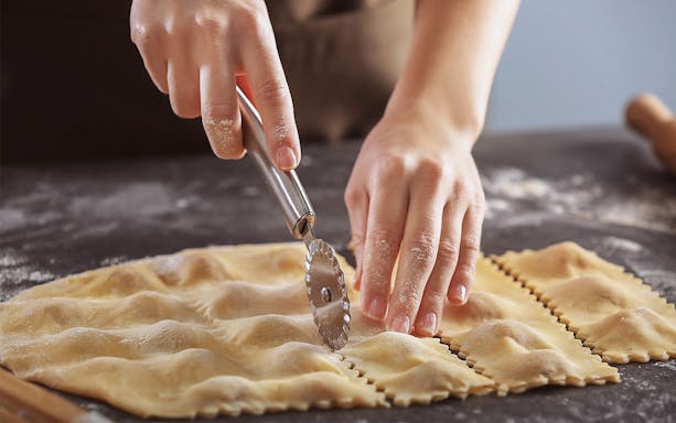 Participants making fettucine and tiramisu during a cooking class in Rome.