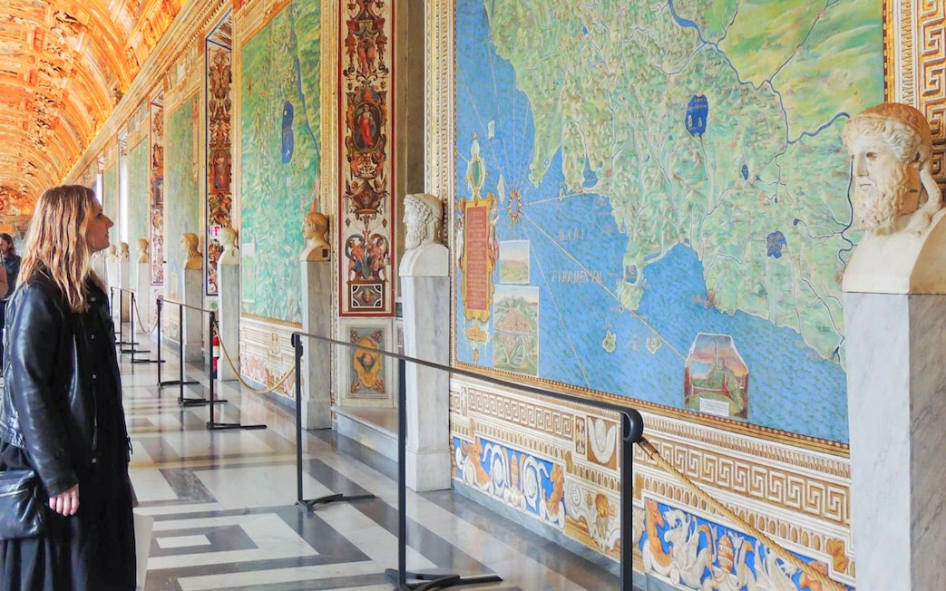 Visitor admiring detailed frescoes in the Vatican Gallery of Maps, Vatican City.