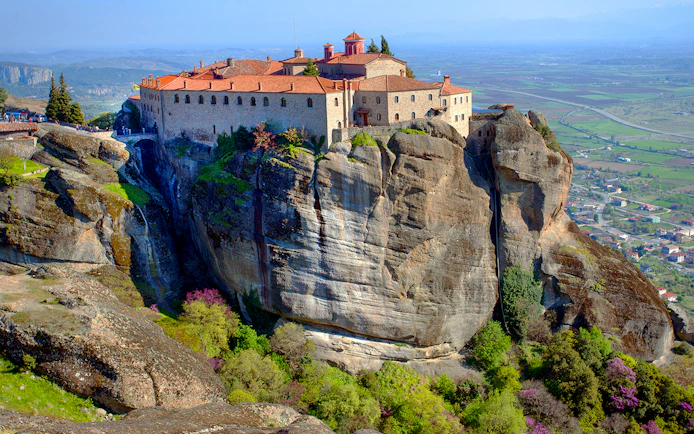 Meteora monastery perched on a rocky cliff with panoramic views of the Thessaly Valley, Greece.