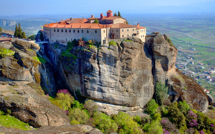 Meteora monastery perched on a rocky cliff with panoramic views of the Thessaly Valley, Greece.