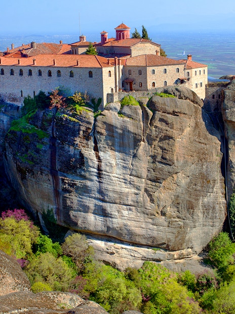 Meteora monastery perched on a rocky cliff with panoramic views of the Thessaly Valley, Greece.