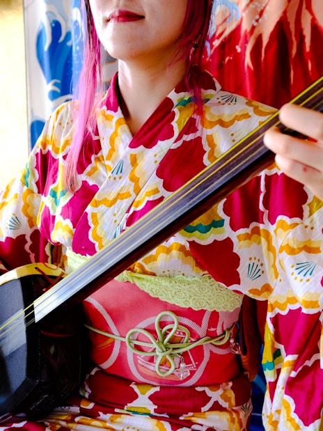 Person playing a shamisen in traditional Japanese attire.