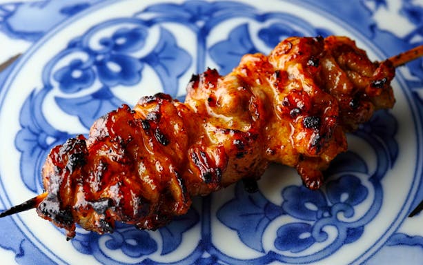 Grilled yakitori skewer on a decorative blue and white plate at Yakitori Tsukiya.