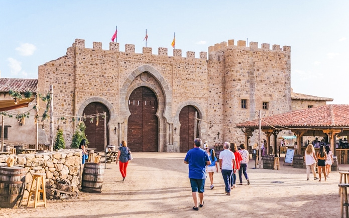 Visitors entering medieval stone gate at Puy du Fou España park.