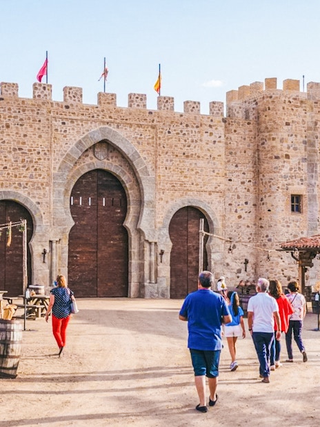 Visitors entering medieval stone gate at Puy du Fou España park.