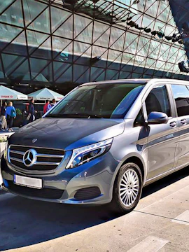 Silver van parked outside John Paul II International Airport terminal.