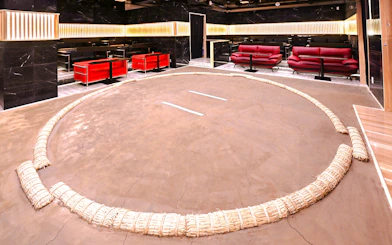 Wrestling ring at Asakusa Sumo club, Tokyo with seating area in background.