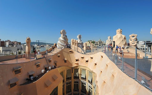 Rooftop view of Casa Milà in Barcelona with unique chimneys and tourists exploring.