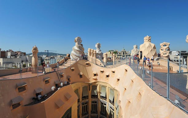 Rooftop view of Casa Milà in Barcelona with unique chimneys and tourists exploring.