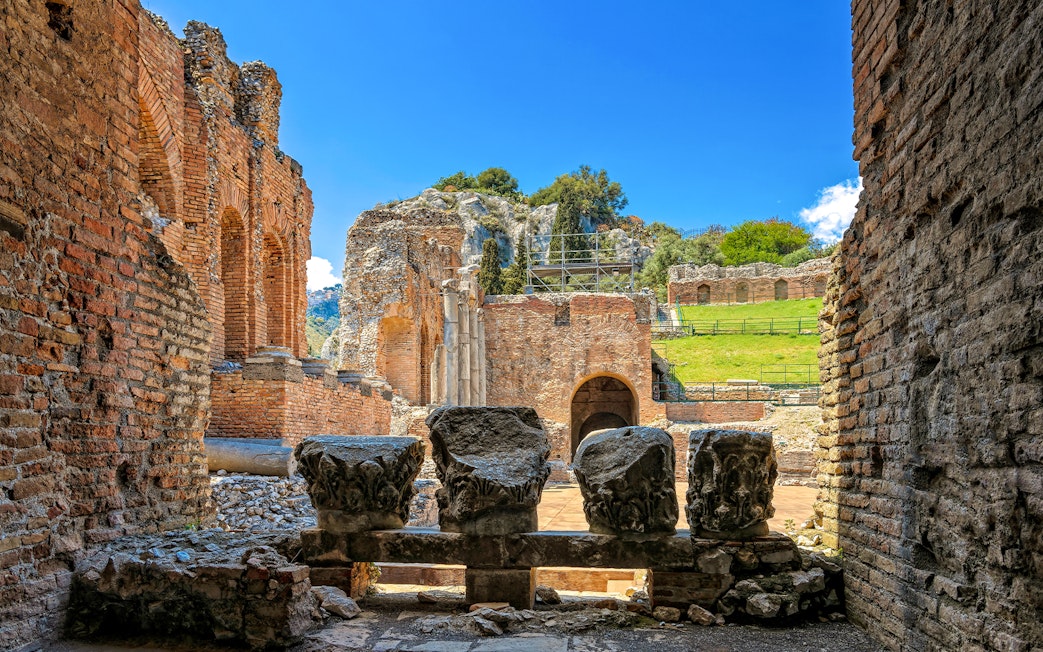 Taormina Ancient Theatre ruins with stone columns and archways, Sicily.