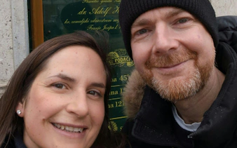 Two people smiling in front of a historic plaque during a self-guided city exploration in Zagreb.