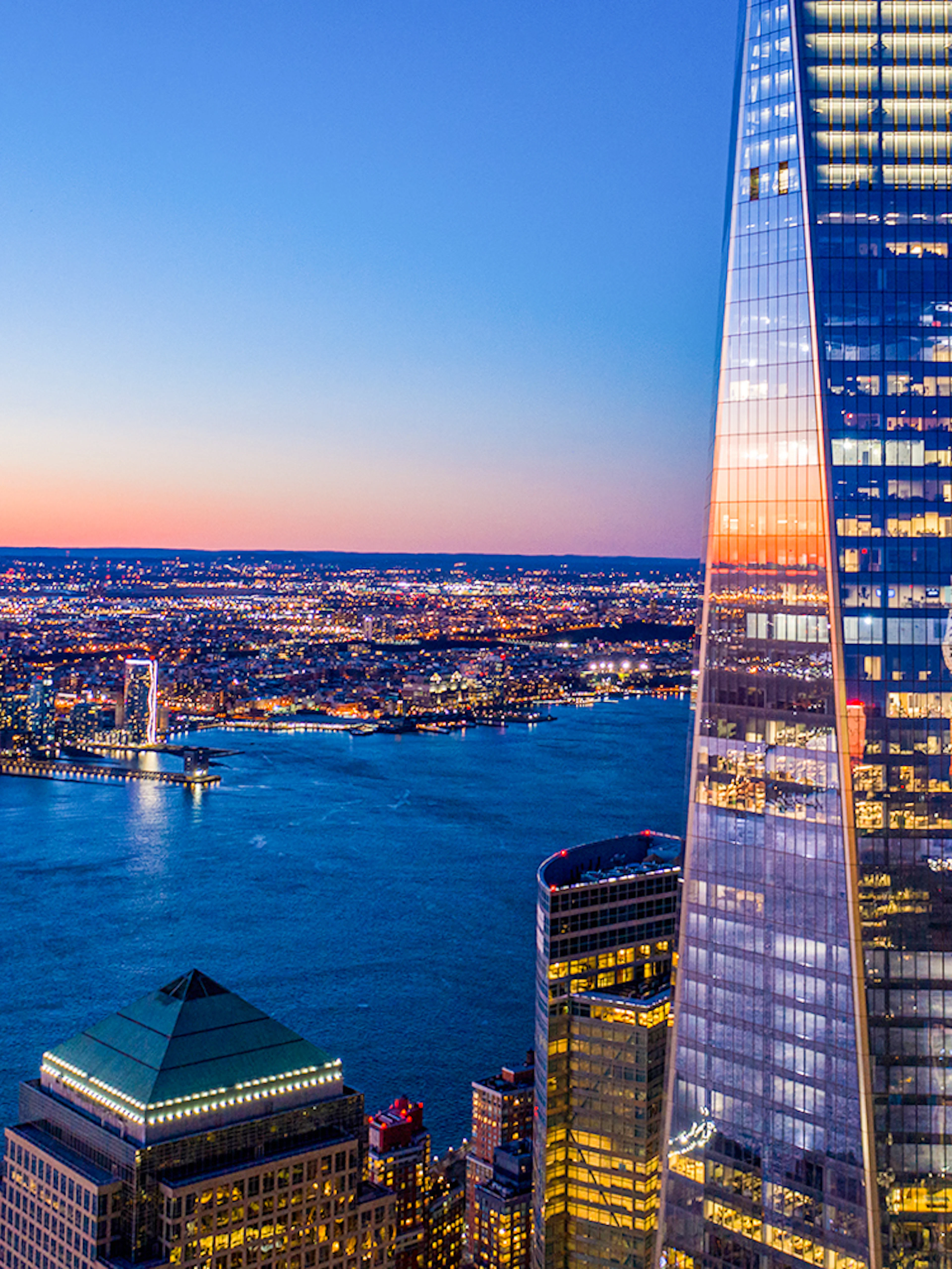 One World Observatory view at sunset over New York City skyline and Hudson River.