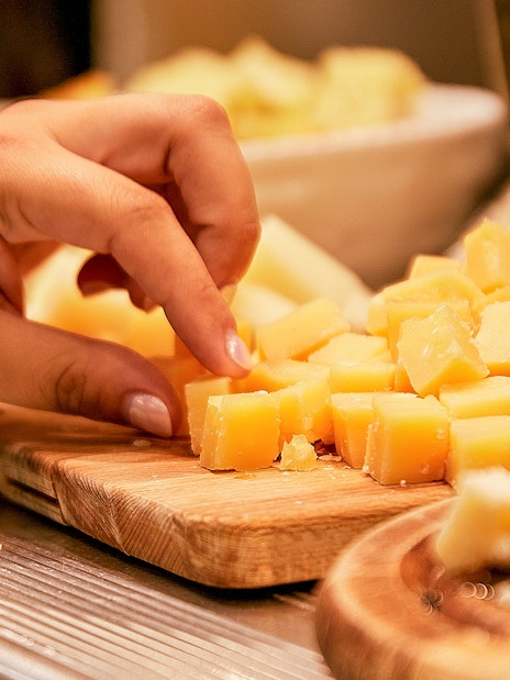 Tourist sampling cheese cubes at a market food tour.