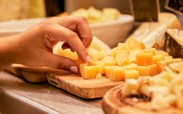 Tourist sampling cheese cubes at a market food tour.