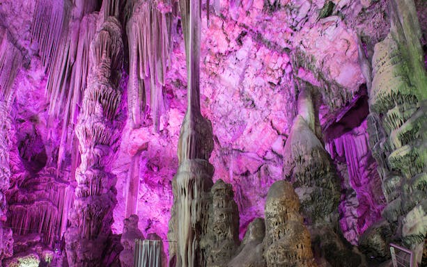 Stalactites and stalagmites in St. Michael's Cave, Gibraltar, illuminated with purple light.