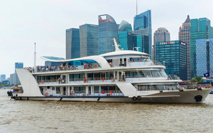 Cruise ship on the Huangpu River with Shanghai skyline in the background.