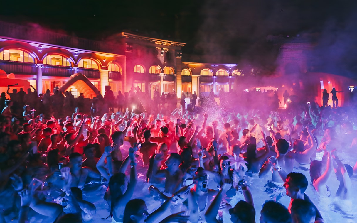 Crowd enjoying Sparty bath party at night in Budapest thermal baths.