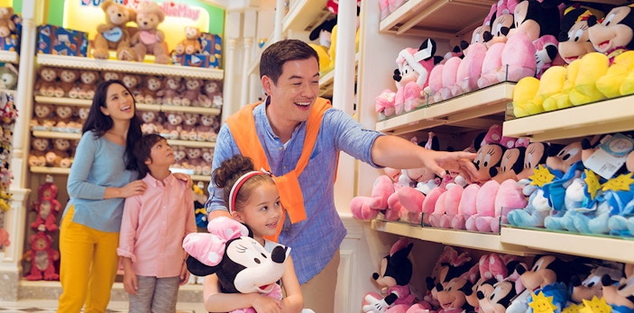 Family shopping for Disney plush toys at Disneyland Hong Kong store.