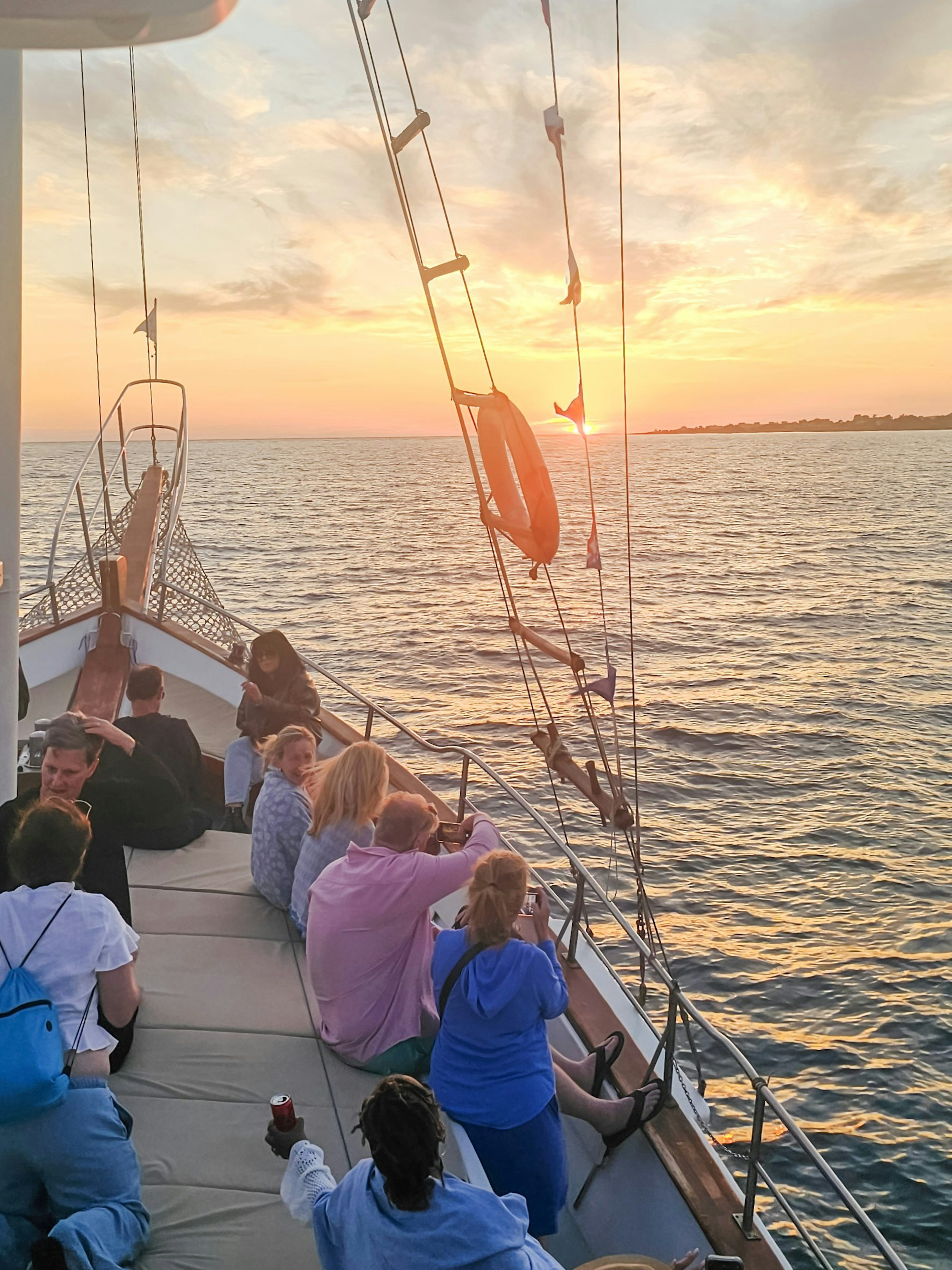 People enjoying a sunset cruise on a boat in Kefalonia, with a view of the sea and horizon.