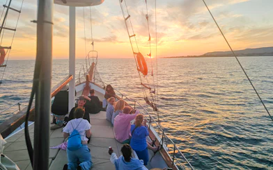 People enjoying a sunset cruise on a boat in Kefalonia, with a view of the sea and horizon.