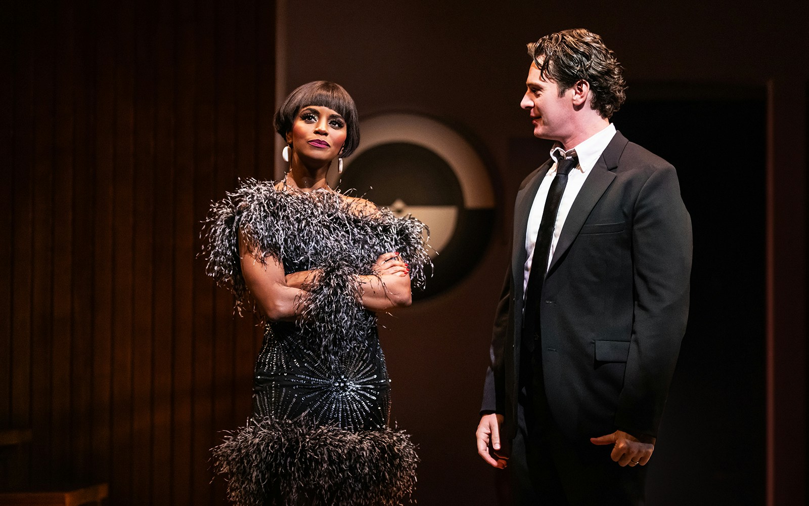 Actors performing in "Merrily We Roll Along" on stage.