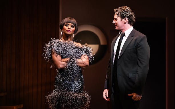 Actors performing in "Merrily We Roll Along" on stage.