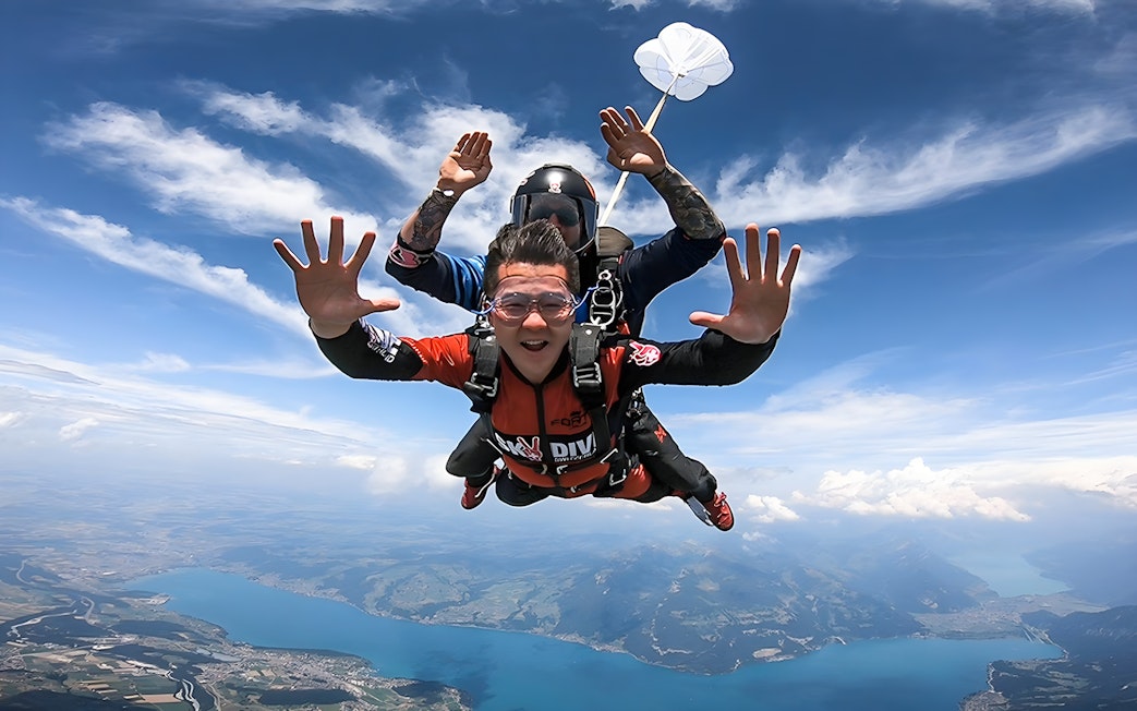 Skydivers tandem freefalling over Lake Thun in Interlaken, Switzerland.