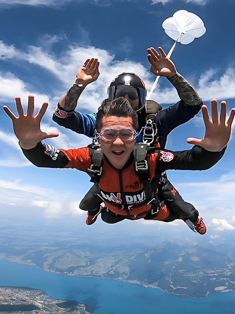 Skydivers tandem freefalling over Lake Thun in Interlaken, Switzerland.