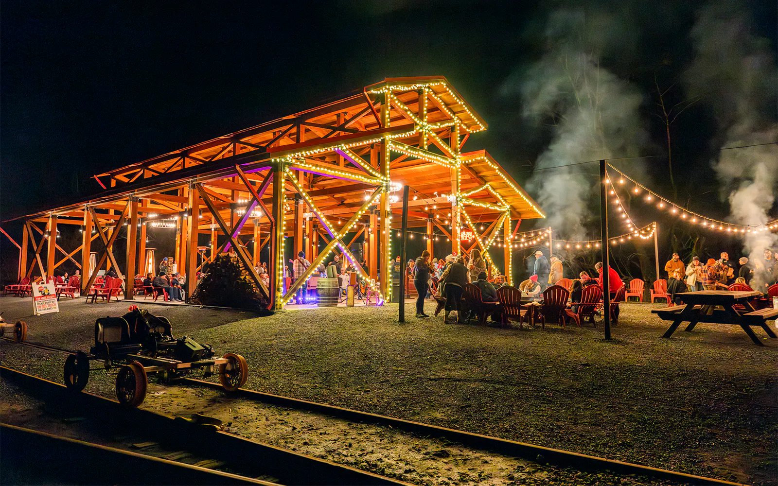 Moonlit gathering at Glen Blair Bar with railbikes on tracks, surrounded by string lights.