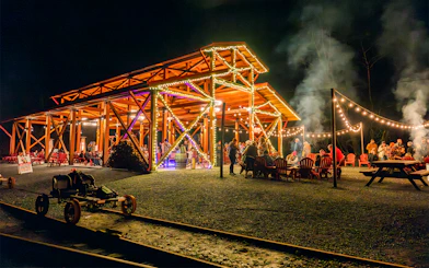 Moonlit gathering at Glen Blair Bar with railbikes on tracks, surrounded by string lights.