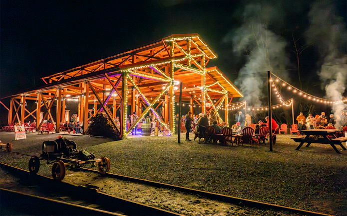 Moonlit gathering at Glen Blair Bar with railbikes on tracks, surrounded by string lights.