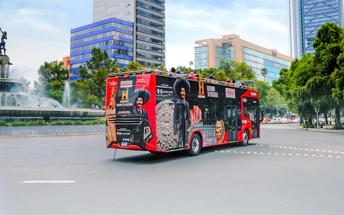 Turibus in Historic Center of Mexico City passing fountain and modern buildings.
