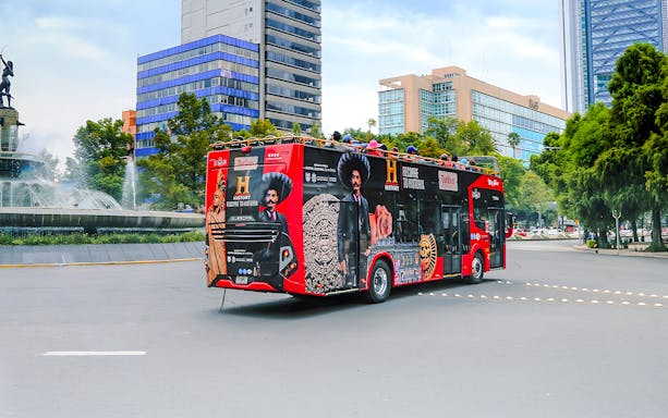 Turibus in Historic Center of Mexico City passing fountain and modern buildings.