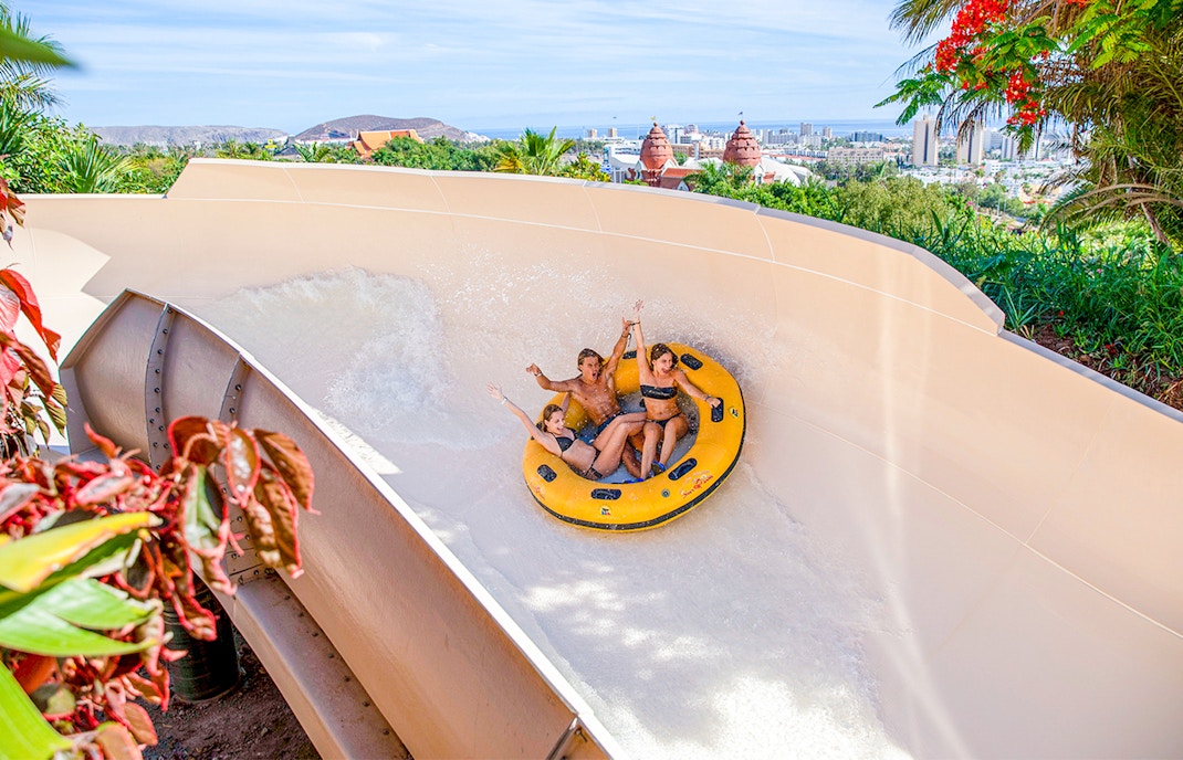 Visitors enjoying the patong rapids ride at Siam Park, Tenerife, with lush greenery in the background.
