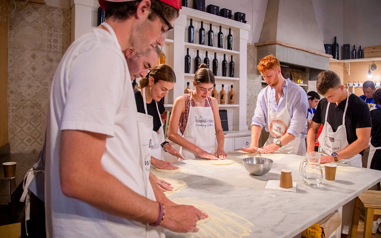 Participants making pizza dough in a cooking class, Italy.