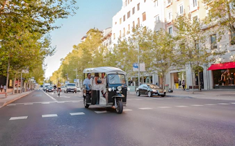 Electric tuk-tuk with passengers on a street in Madrid, Spain.