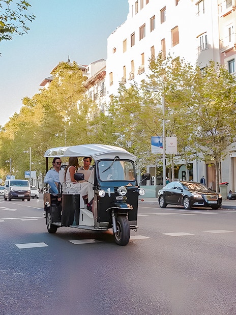 Electric tuk-tuk with passengers on a street in Madrid, Spain.