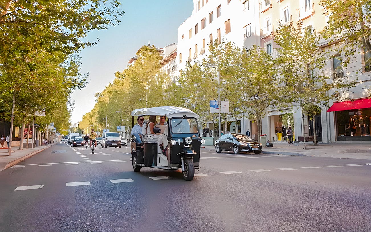 Electric tuk-tuk with passengers on a street in Madrid, Spain.