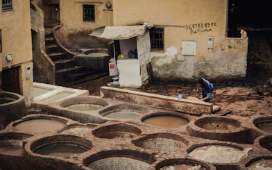 Tannery worker in Fes Old Medina preparing leather in traditional dyeing vats.