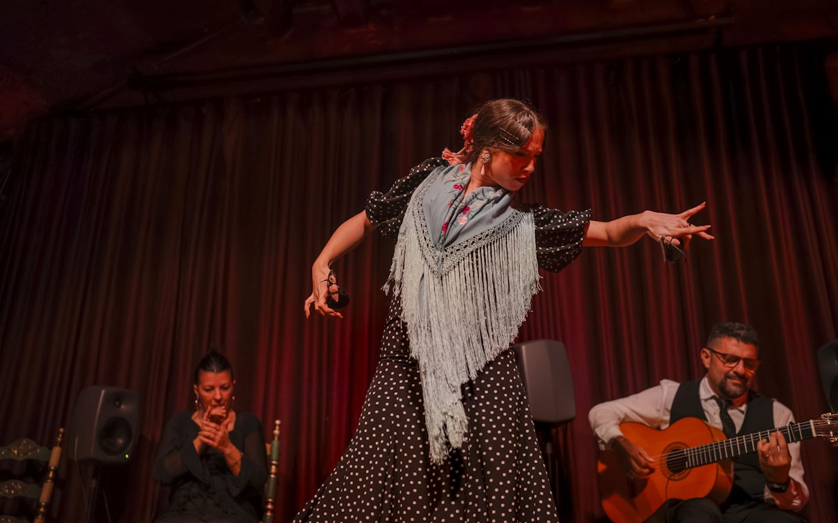 Flamenco dancer performing at Palau Dalmases with guitarist and singer.
