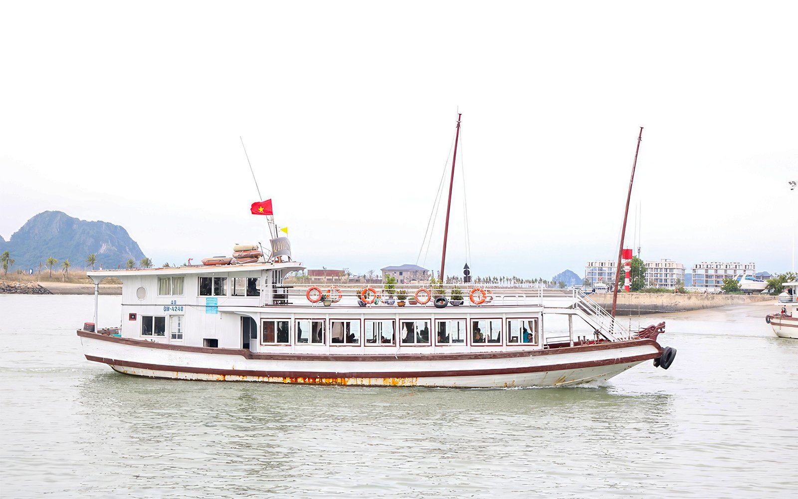 Dragonfly Standard Cruise boat on Halong Bay with Vietnamese flag.