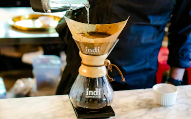 Pouring water over coffee grounds in a Chemex during a VIP morning market experience.