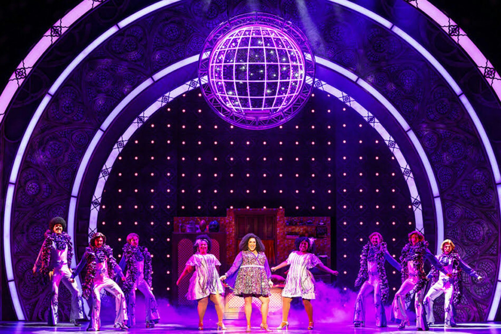 Performers on stage in a vibrant "Sister Act" musical scene with disco ball.