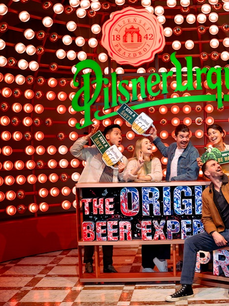 Group enjoying Prague Pilsner Urquell Experience with beer signs and lights.