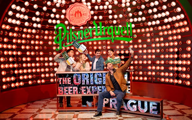 Group enjoying Prague Pilsner Urquell Experience with beer signs and lights.