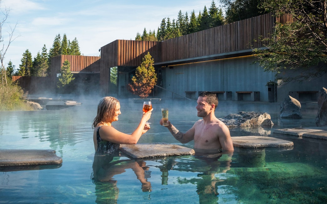 Couple enjoying drinks in Forest Lagoon geothermal spa, Vaðlaskógur forest, near Akureyri, North Iceland.