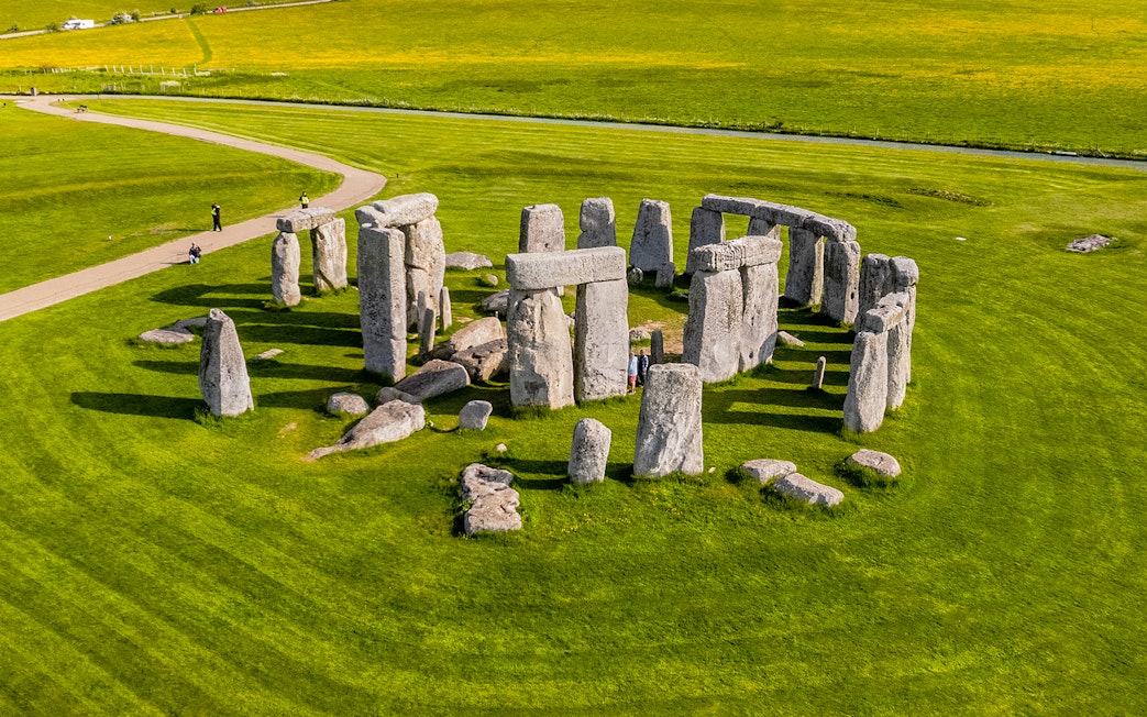 Tourists walking around Stonehenge on a day trip from London.