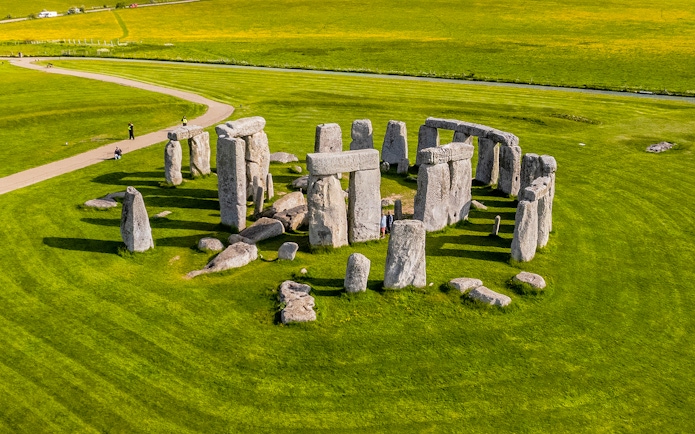 Tourists walking around Stonehenge on a day trip from London.