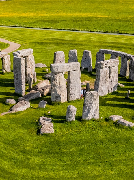 Tourists walking around Stonehenge on a day trip from London.